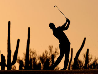 Luke Donald hits an iron in the late desert sun